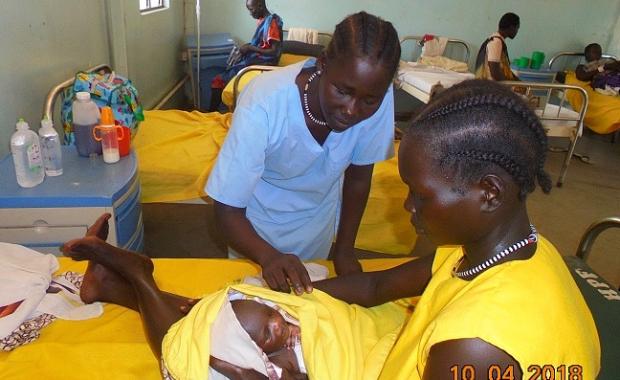 A nurse with a mother and her newborn on the maternity ward