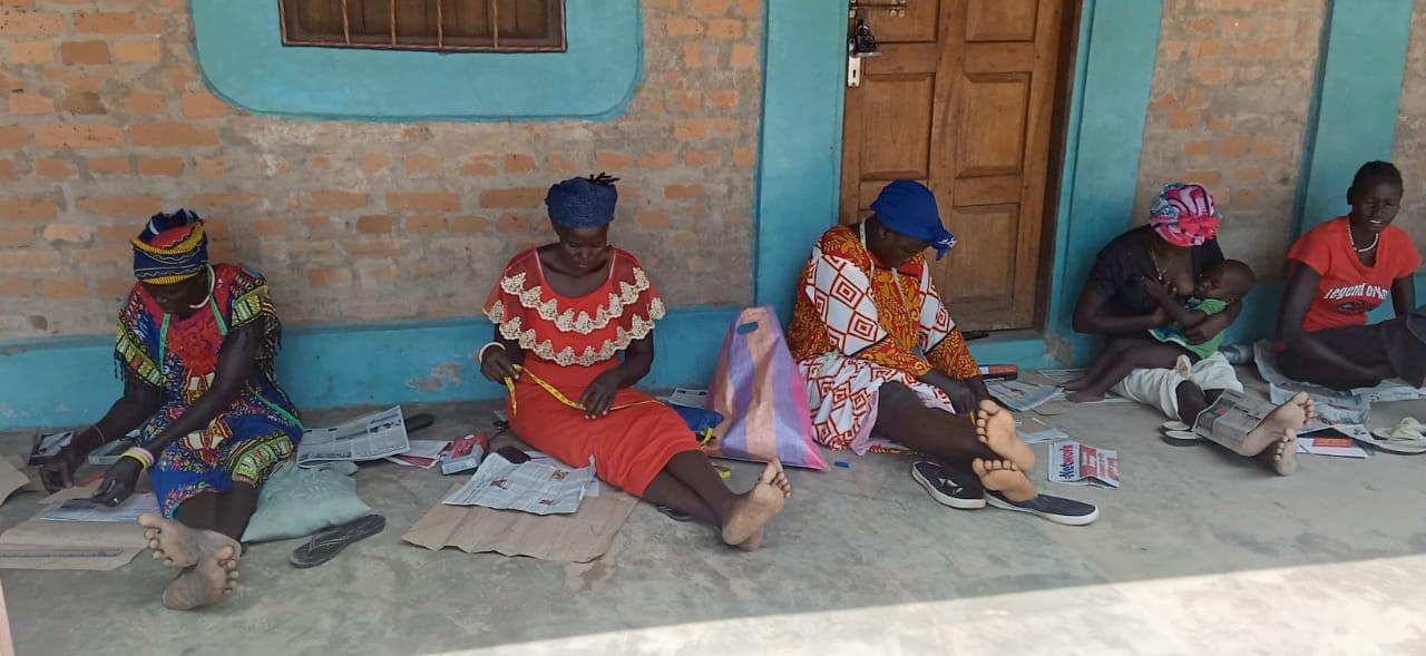Women cutting and measuring cloth on a veranda