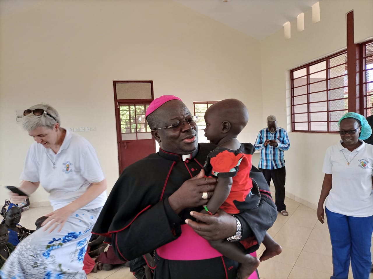 H.L. Bp. Matthew Remijio, Apostolic Administrator carrying a child at Loreto Sisters